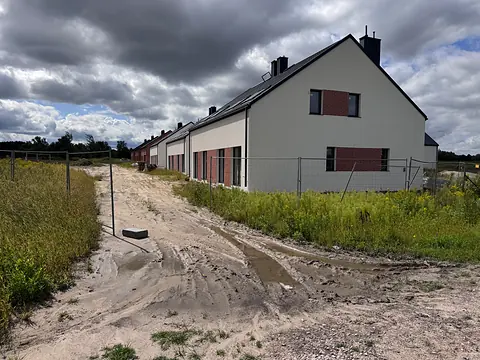 Domy osiedla widziane od strony drogi dojazdowej, sierpień 2026
